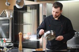 Closeup of a concentrated male chef garnishing food in the kitchen photo