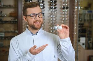 Doctor holds in his hand container with soft contact lenses for single use. Ophthalmologist prescribes use of one-day contact lenses for vision correction. Myopia and eyesight problem concept. photo