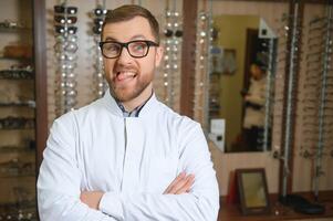 Handsome middle aged ophthalmologist looking at camera and smiling while standing in his office photo
