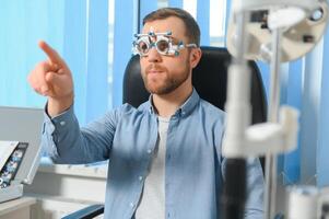 Handsome young man is checking the eye vision in modern ophthalmology clinic. Patient in ophthalmology clinic photo