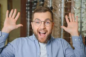 Young man choosing spectacles at optic shop photo