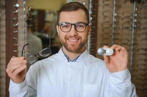 Eye doctor choosing between eyeglasses and lenses standing in the cabinet photo