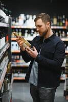 Man in a supermarket choosing a wine photo