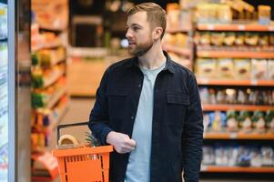 Portrait of smiling man walking with his trolley on aisle at supermarket. photo