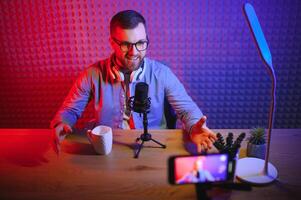 vlogger using smartphone to film podcast in studio. blogger with mobile phone, microphone and headphones filming for social media broadcasting career. photo