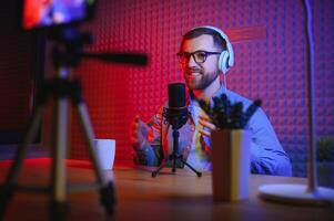 vlogger using smartphone to film podcast in studio. blogger with mobile phone, microphone and headphones filming for social media broadcasting career. photo