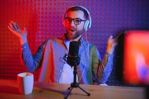 vlogger using smartphone to film podcast in studio. blogger with mobile phone, microphone and headphones filming for social media broadcasting career. photo