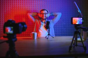 Young man recording or streaming podcast using microphone at his small broadcast studio. Content creator. photo