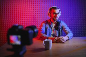 Young man recording or streaming podcast using microphone at his small broadcast studio. Content creator. photo
