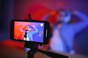 Young man recording or streaming podcast using microphone at his small broadcast studio. Content creator. photo