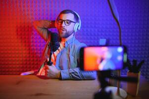 vlogger using smartphone to film podcast in studio. blogger with mobile phone, microphone and headphones filming for social media broadcasting career. photo