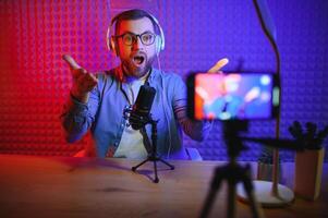 Young man recording or streaming podcast using microphone at his small broadcast studio. Content creator. photo