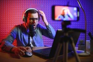 vlogger using smartphone to film podcast in studio. blogger with mobile phone, microphone and headphones filming for social media broadcasting career. photo