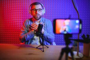 Young man recording or streaming podcast using microphone at his small broadcast studio. Content creator. photo