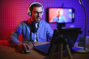 vlogger using smartphone to film podcast in studio. blogger with mobile phone, microphone and headphones filming for social media broadcasting career. photo