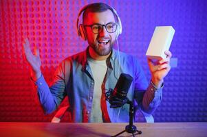 Young man recording or streaming podcast using microphone at his small broadcast studio. Content creator. photo