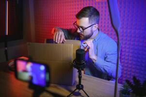 Joyful young man recording unboxing in studio photo