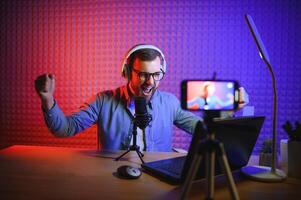 Young man recording or streaming podcast using microphone at his small broadcast studio. Content creator. photo