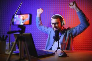 Young man recording or streaming podcast using microphone at his small broadcast studio. Content creator. photo