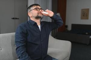 Portrait of man with a nasal spray. Sick man using nose drops while laying at the bed. Concept of treatment for allergies or the common cold, winter style. photo