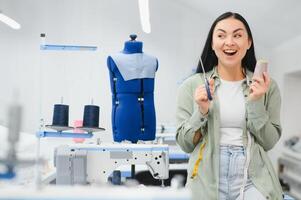 Portrait of a beautiful seamstress carrying a tape measure and working in a textile factory photo