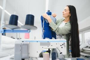 Portrait of a beautiful seamstress carrying a tape measure and working in a textile factory photo