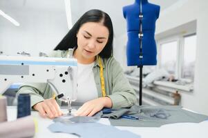 Portrait of a beautiful seamstress carrying a tape measure and working in a textile factory photo
