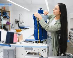 Portrait of a beautiful seamstress carrying a tape measure and working in a textile factory photo