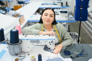 Portrait of a beautiful seamstress carrying a tape measure and working in a textile factory photo