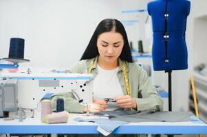 Portrait of a beautiful seamstress carrying a tape measure and working in a textile factory photo