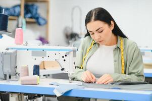Portrait of a beautiful seamstress carrying a tape measure and working in a textile factory photo
