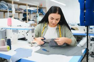 Portrait of a beautiful seamstress carrying a tape measure and working in a textile factory photo