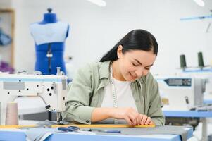 Portrait of a beautiful seamstress carrying a tape measure and working in a textile factory photo