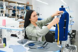 Portrait of a beautiful seamstress carrying a tape measure and working in a textile factory photo