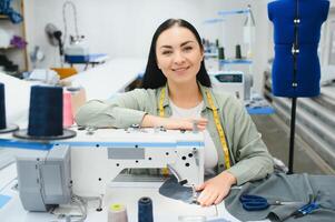 Portrait of a beautiful seamstress carrying a tape measure and working in a textile factory photo