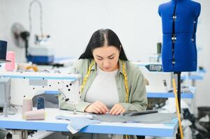 Portrait of a beautiful seamstress carrying a tape measure and working in a textile factory photo