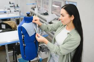 Portrait of a beautiful seamstress carrying a tape measure and working in a textile factory photo