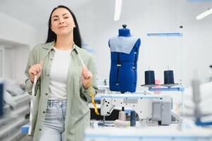 Portrait of a beautiful seamstress carrying a tape measure and working in a textile factory photo