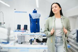 Portrait of a beautiful seamstress carrying a tape measure and working in a textile factory photo