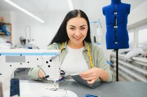Portrait of a beautiful seamstress carrying a tape measure and working in a textile factory photo
