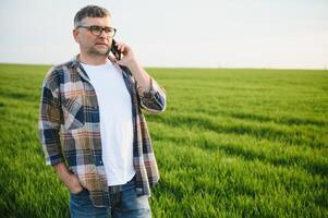 Portrait of senior farmer standing in wheat field examining crop during the day. photo