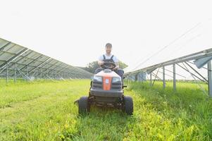 A man mows the grass near the solar panels. Green energy photo