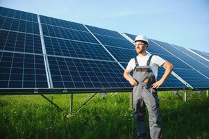 Side view of male worker installing solar modules and support structures of photovoltaic solar array. Electrician wearing safety helmet while working with solar panel. Concept of sun energy photo