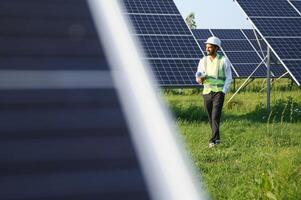 Portrait of Young indian male engineer standing near solar panels, with clear blue sky background, Renewable and clean energy. skill india, copy space. photo