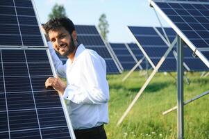 Portrait of Young indian male engineer standing near solar panels, with clear blue sky background, Renewable and clean energy. skill india, copy space. photo