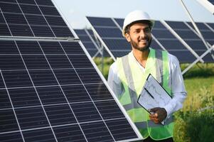 Portrait of Young indian male engineer standing near solar panels, with clear blue sky background, Renewable and clean energy. skill india, copy space. photo