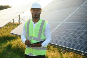 Young African American engineer in a field of solar panels. photo