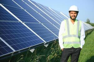 Portrait of Young indian male engineer standing near solar panels, with clear blue sky background, Renewable and clean energy. skill india, copy space. photo