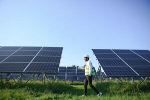 Portrait of Young indian male engineer standing near solar panels, with clear blue sky background, Renewable and clean energy. skill india, copy space. photo