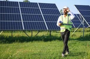 Portrait of Young indian male engineer standing near solar panels, with clear blue sky background, Renewable and clean energy. skill india, copy space. photo